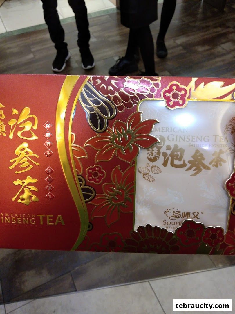 A red gift box with gold floral designs containing American Ginseng Tea.