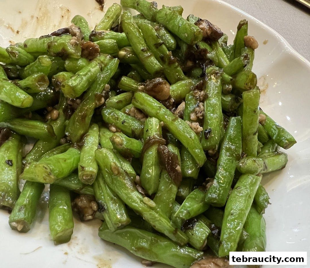 A close-up shot of stir-fried green beans with minced meat and mushrooms.