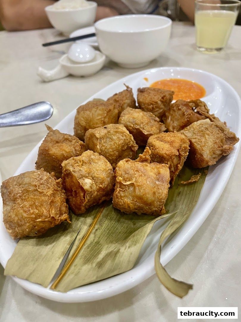 A plate of crispy fried tofu skin rolls served with dipping sauce and rice.