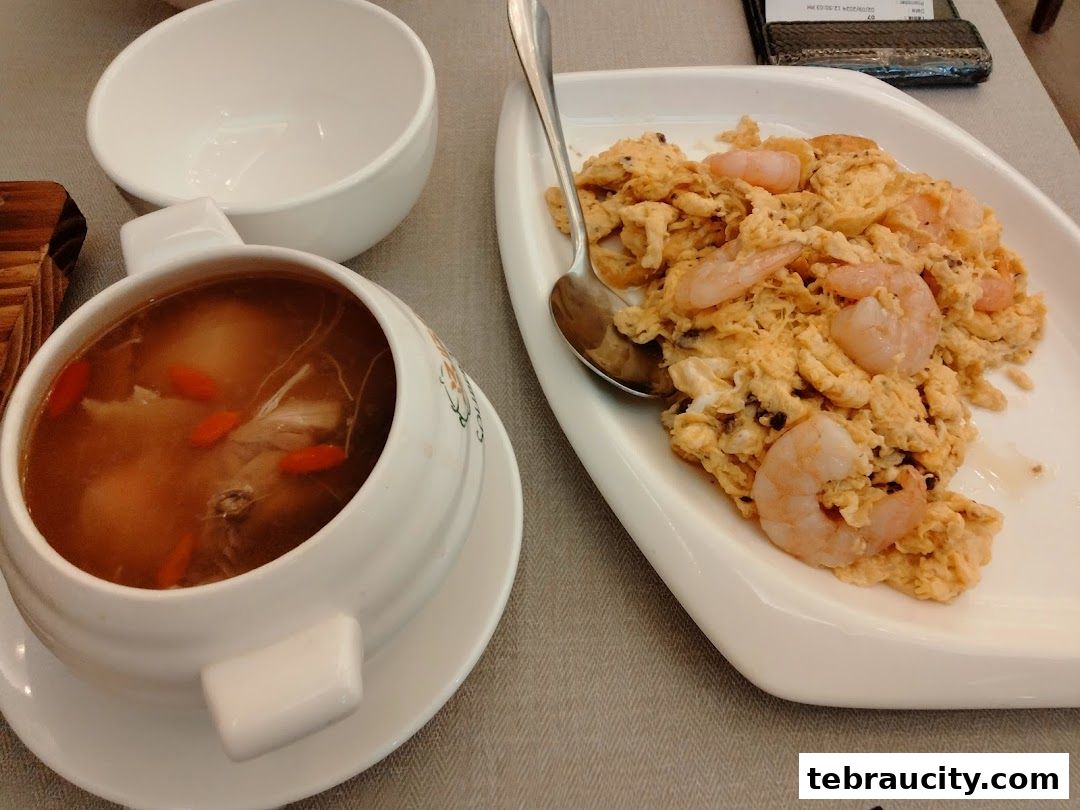 A bowl of soup with goji berries and a plate of scrambled eggs with shrimp.