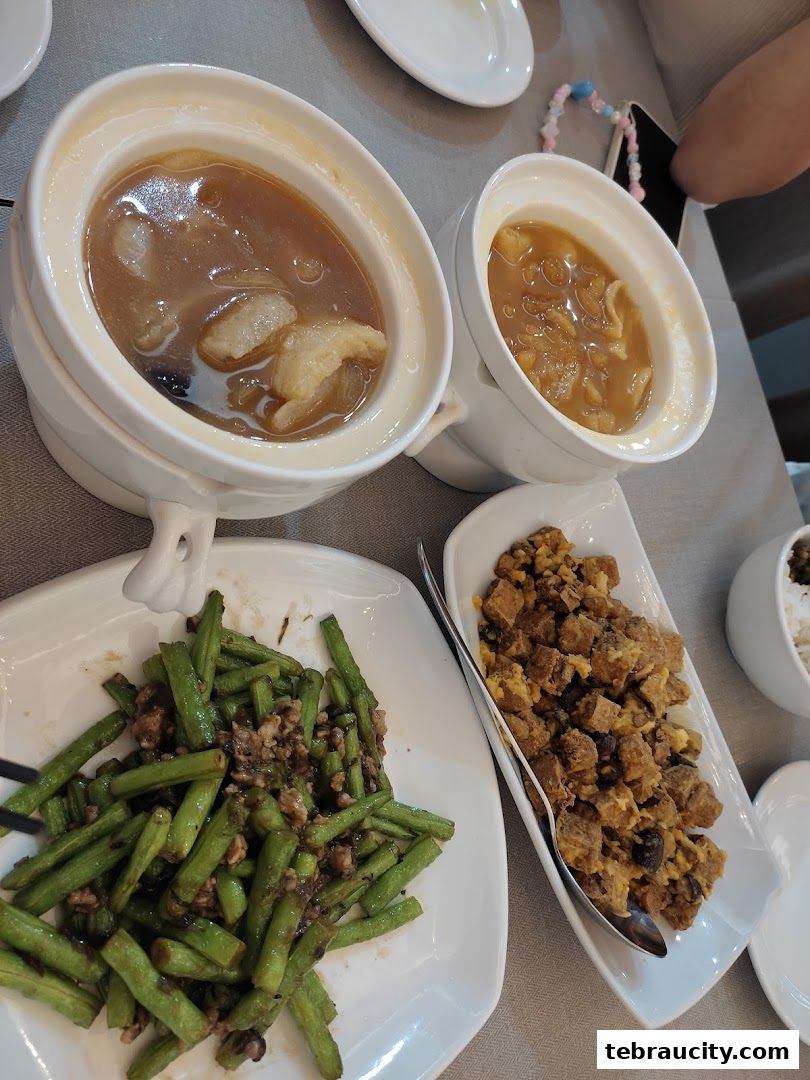 A table setting with various dishes, including soups, stir-fried green beans, and a crispy dish.