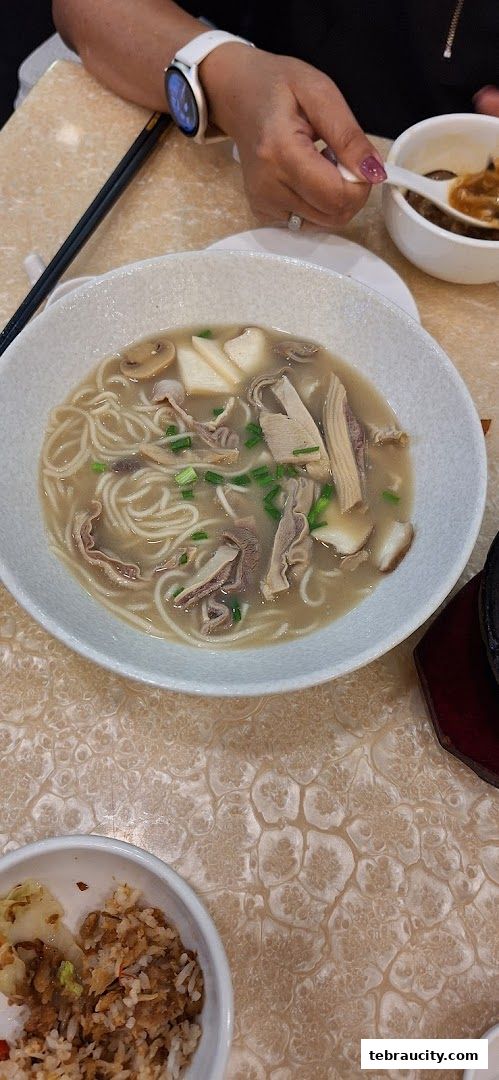 A bowl of noodle soup with meat and mushrooms, served with a side of fried rice.