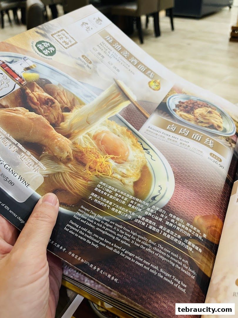 A person holding a menu featuring two noodle dishes from Souper Tang.