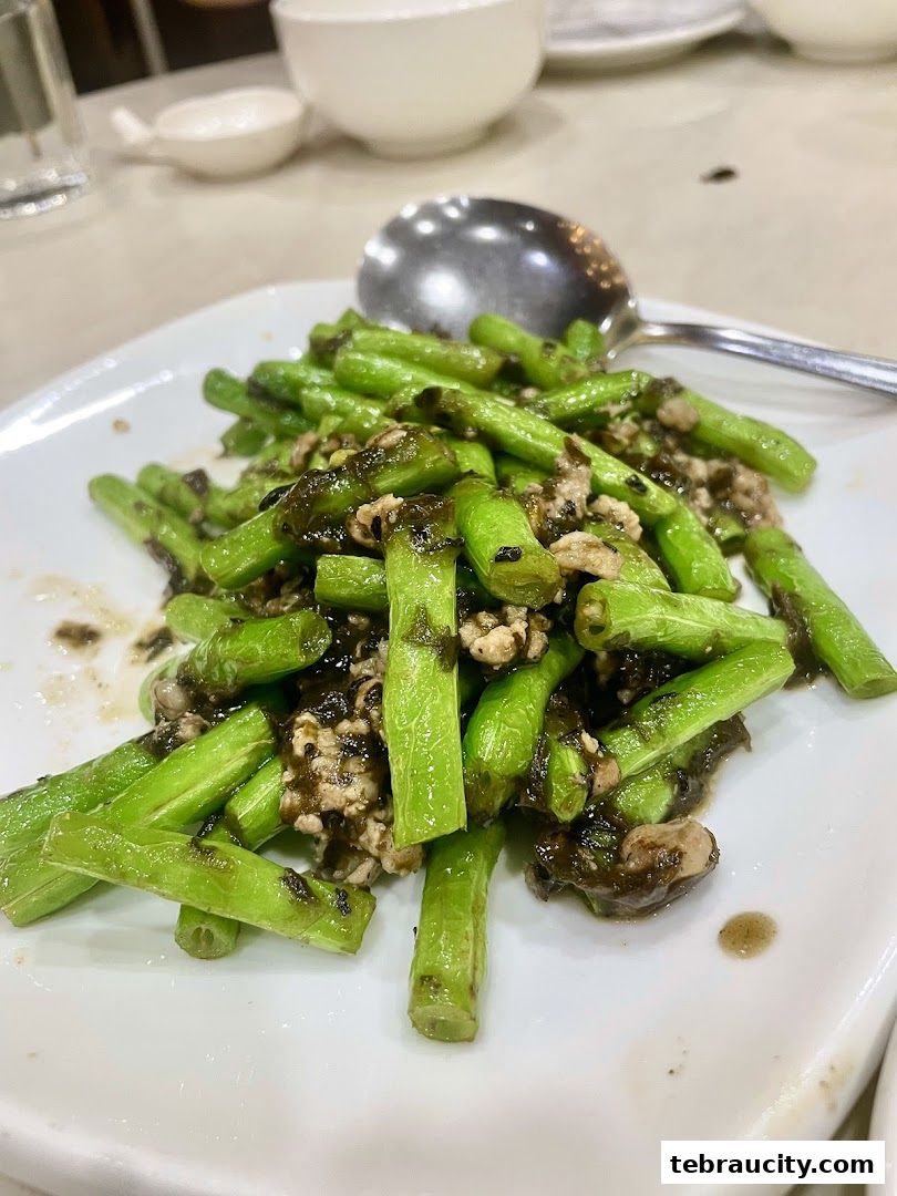 A plate of stir-fried green beans with minced meat and a savory sauce.