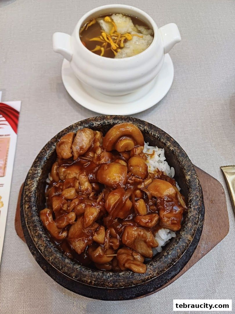 A stone bowl filled with rice and glazed chicken, served with a small bowl of soup.