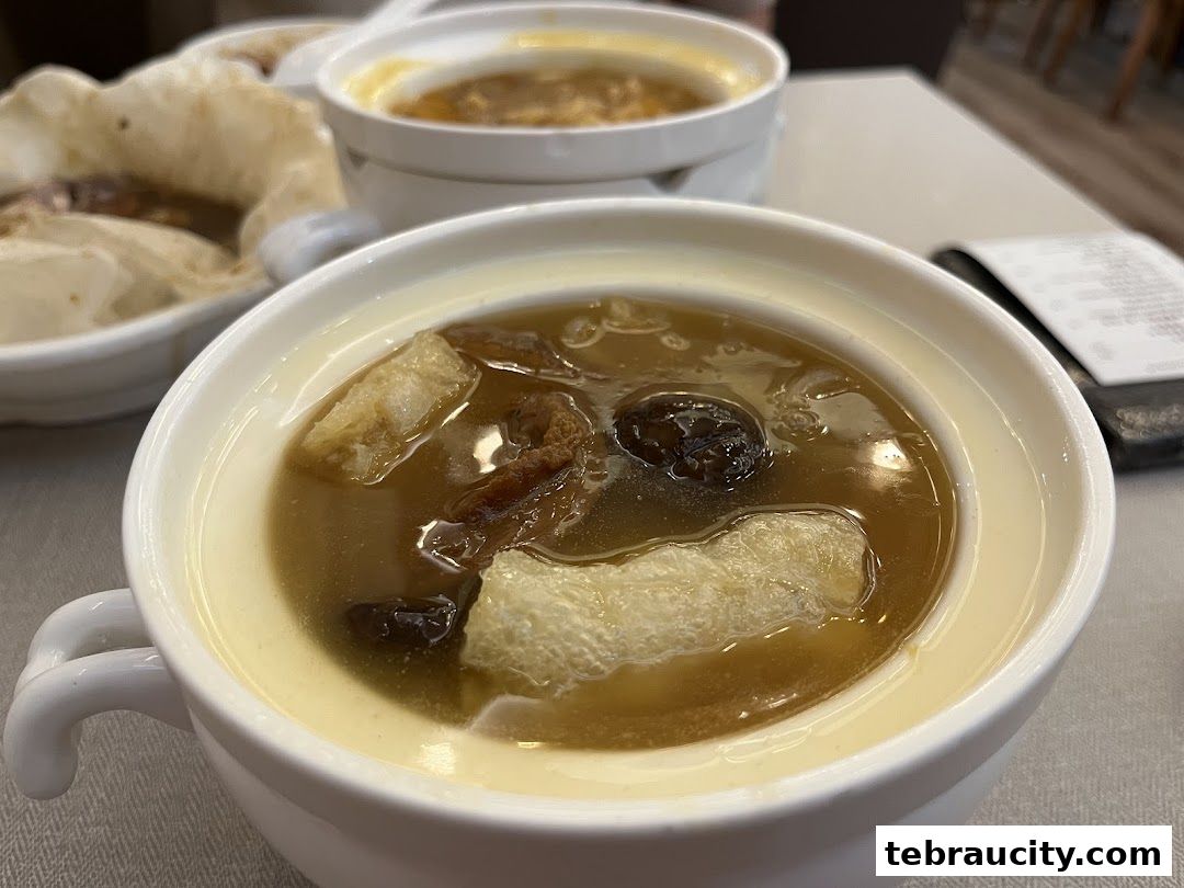 Close-up of a steaming bowl of soup with various ingredients, including what appears to be fish maw.