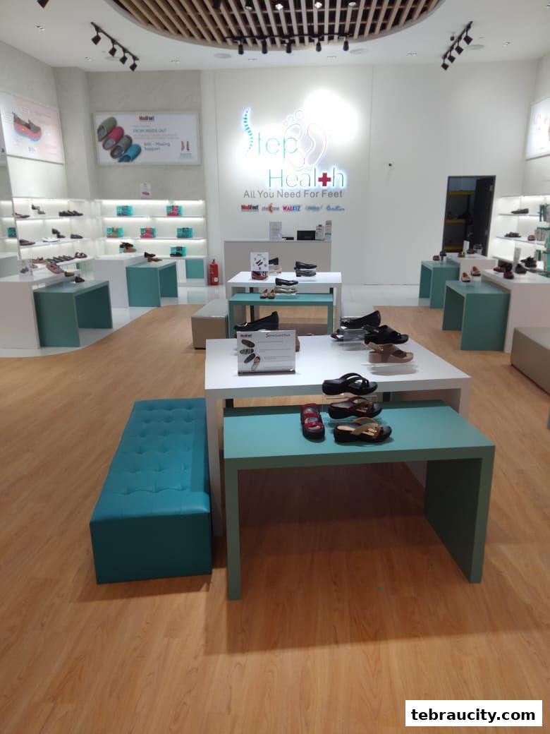 Interior view of a modern shoe store with various footwear displayed on shelves and tables.