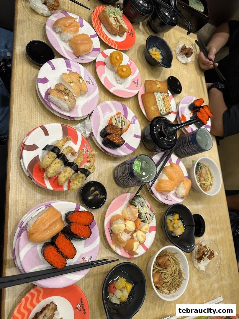 A table filled with various plates of sushi, appetizers, and drinks at Sushi King.