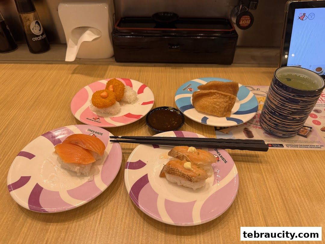 A table at Sushi King with various sushi dishes, a cup of green tea, and chopsticks.