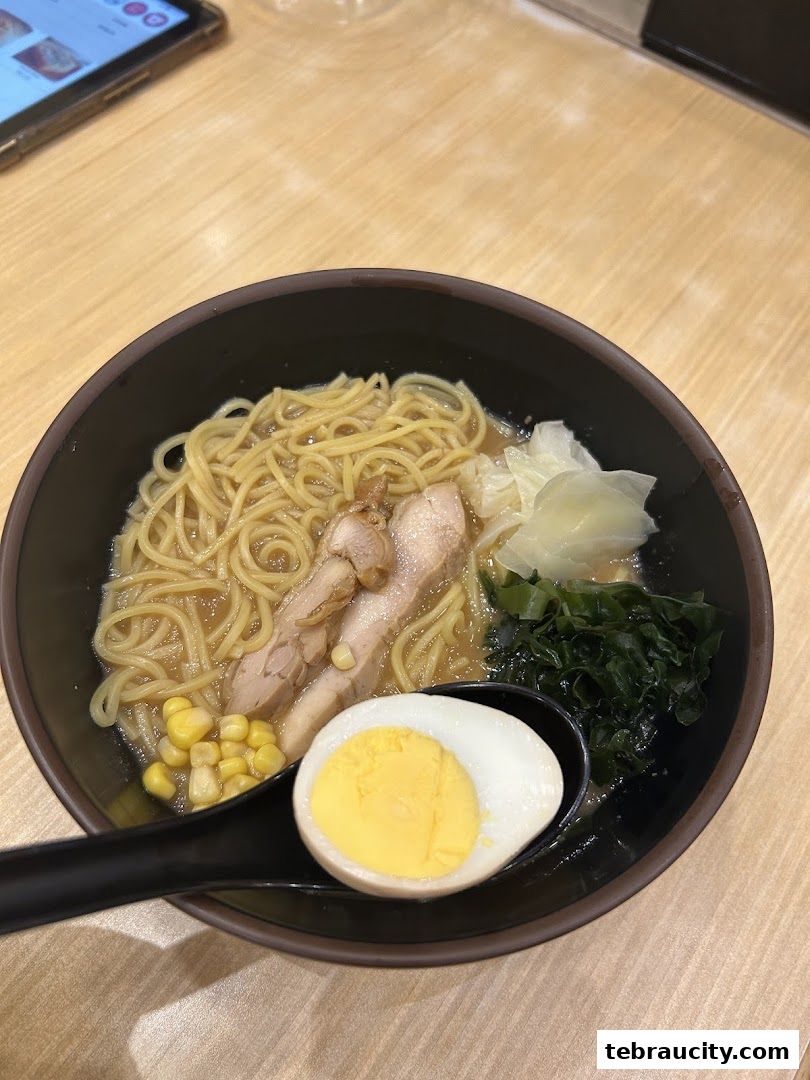 A close-up of a delicious bowl of ramen with pork, egg, corn, and seaweed.