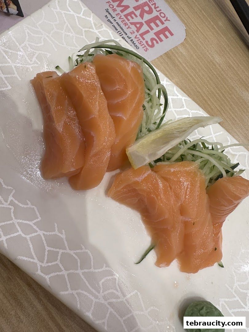 Fresh salmon sashimi served with shredded cucumber and a dollop of wasabi.