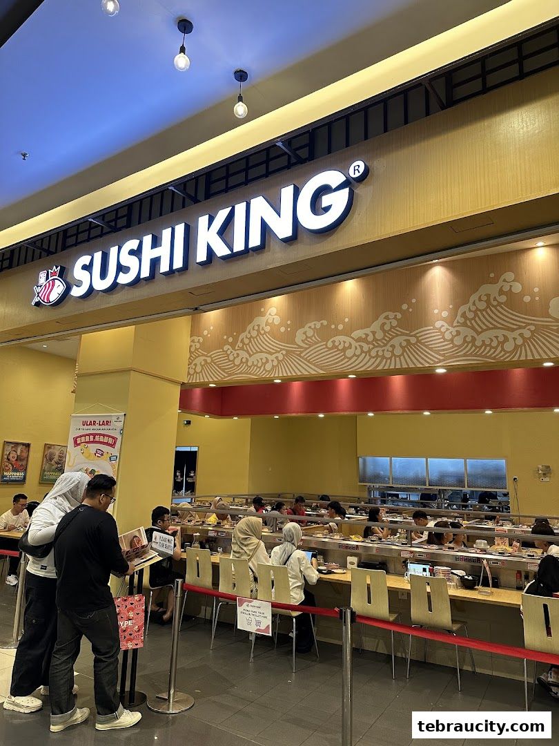 Sushi King restaurant interior with customers seated at a conveyor belt sushi bar.