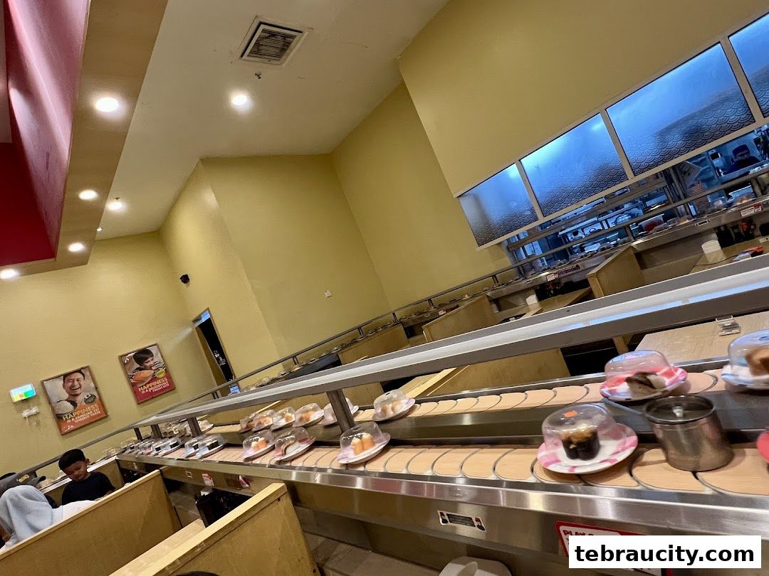 Interior of a sushi restaurant with a conveyor belt filled with various sushi dishes.