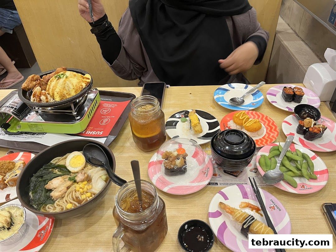 A table full of various sushi dishes, ramen, and drinks at Sushi King.