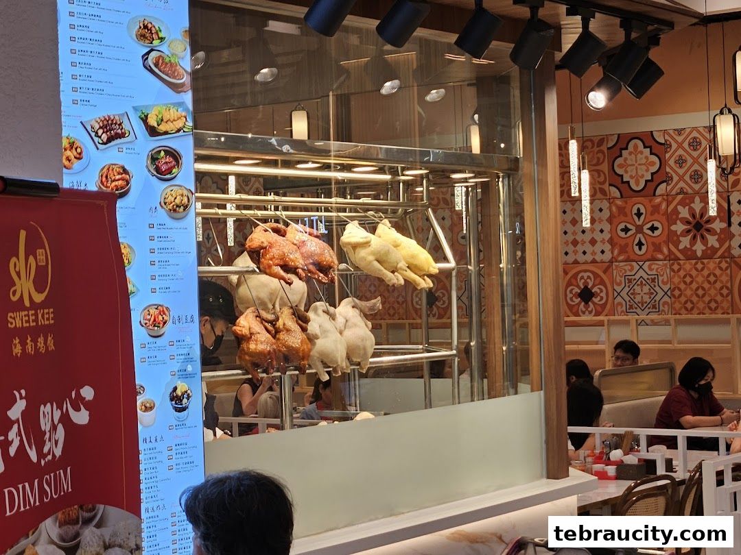 A display of roasted chickens and a menu board at Swee Kee Chicken Rice.
