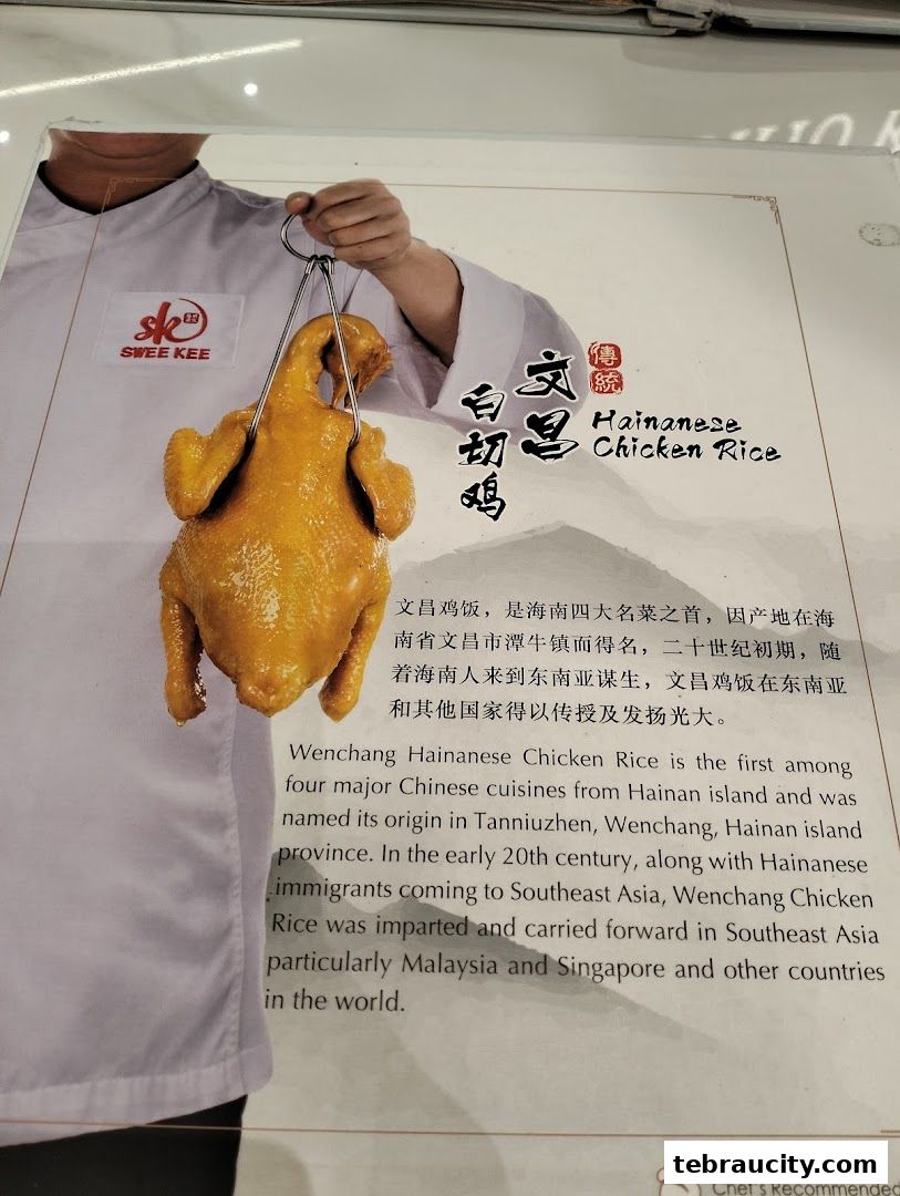 A chef holds a whole roasted chicken, advertising Hainanese Chicken Rice.