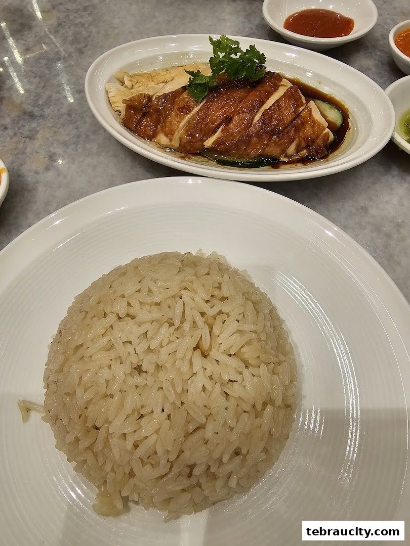 A close-up shot of a plate of delicious chicken rice with a side of chili sauce.