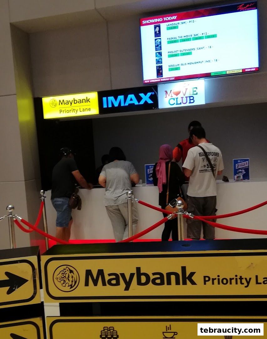 People queuing at a cinema ticket counter with a 'Showing Today' screen and IMAX branding.