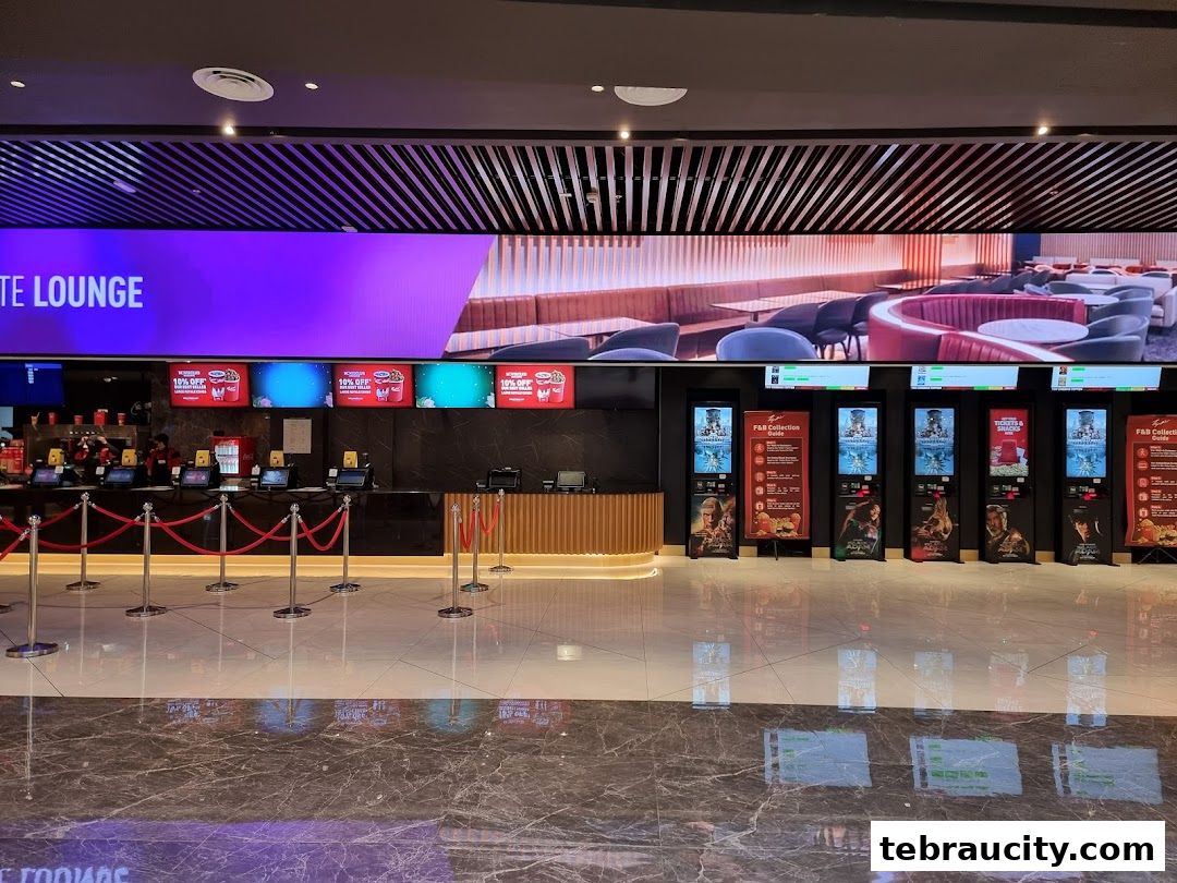 The interior of a modern cinema lobby with ticket counters and digital displays.