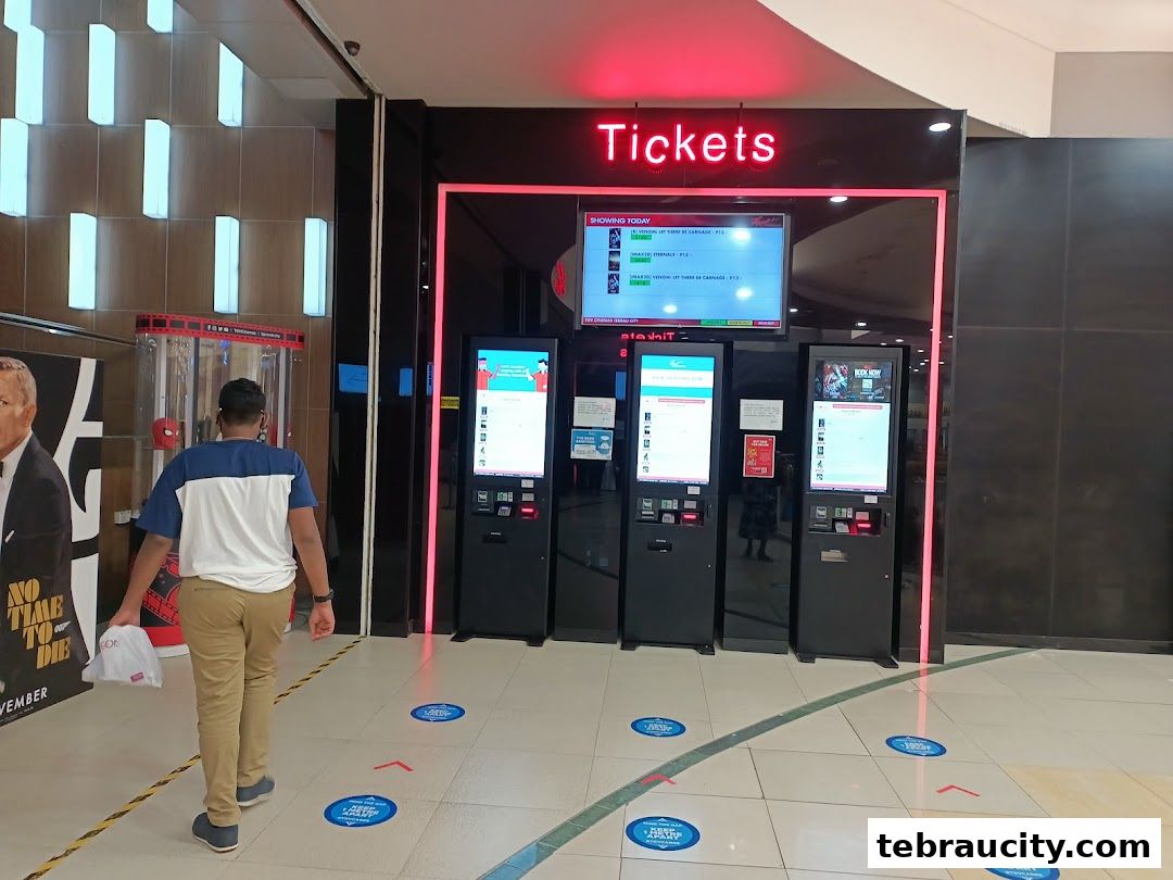 A person walks towards ticket kiosks at a cinema entrance with movie posters.