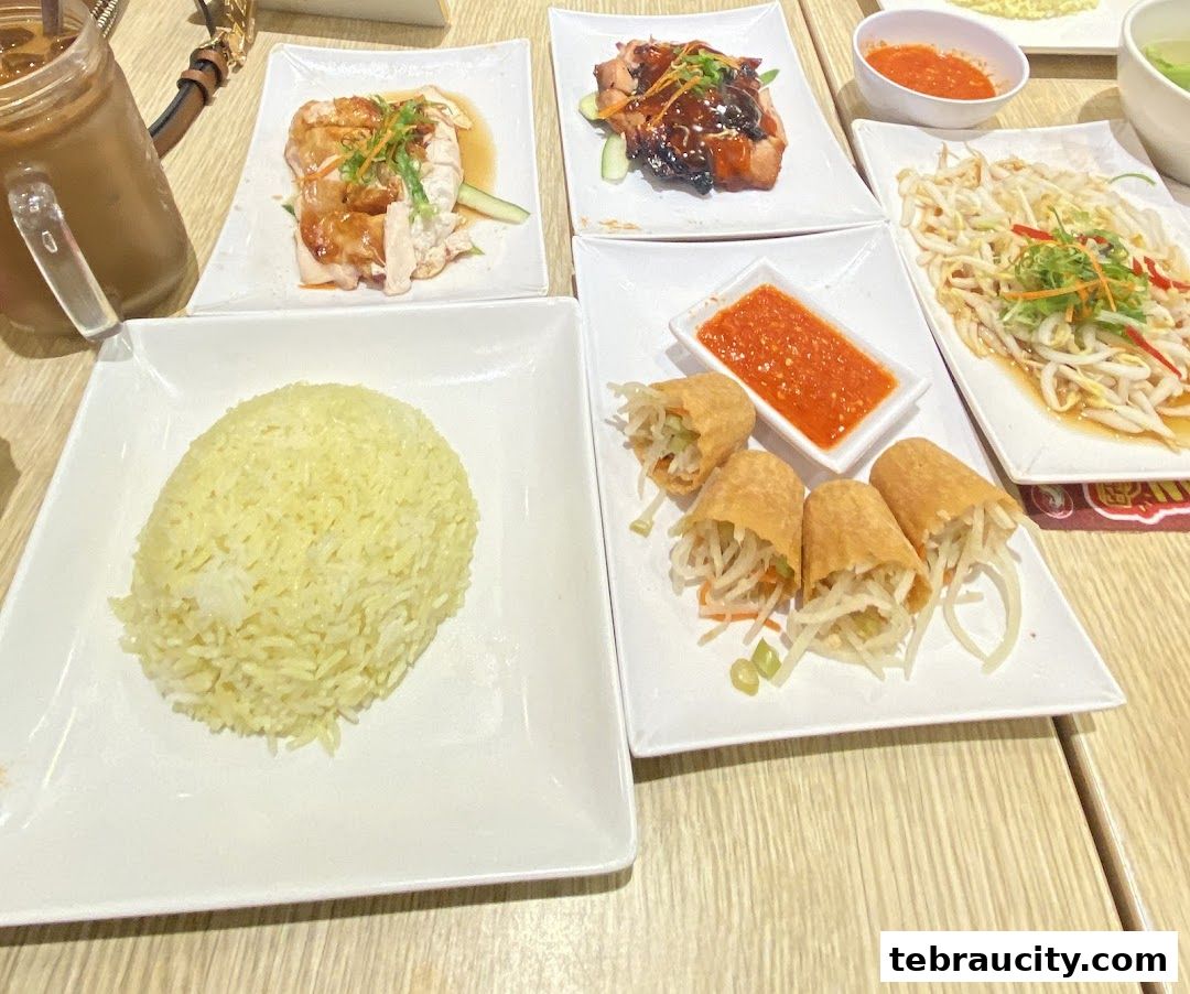 A table laden with delicious chicken rice, roasted chicken, spring rolls, and bean sprouts.