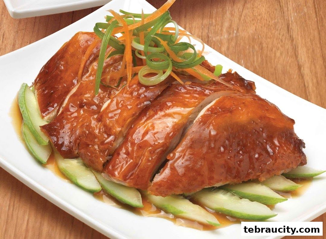 A plate of sliced roasted chicken with cucumber and garnished with shredded carrots and scallions.