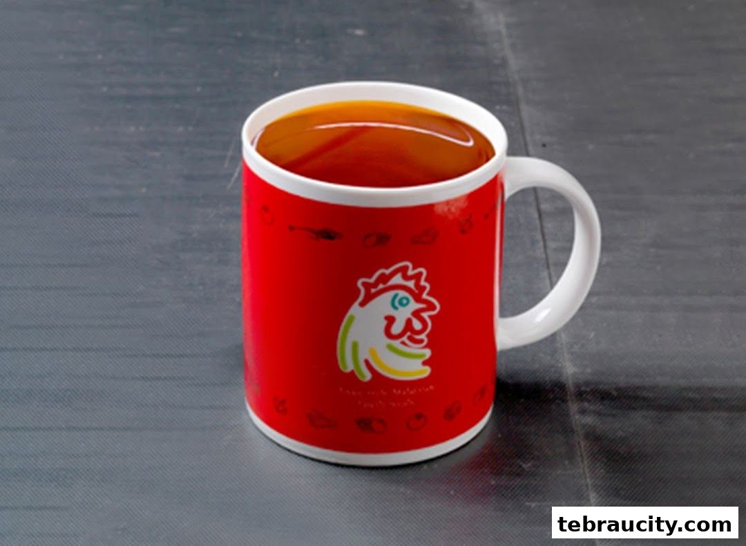 A red mug with the Chicken Rice Shop logo filled with a dark beverage.