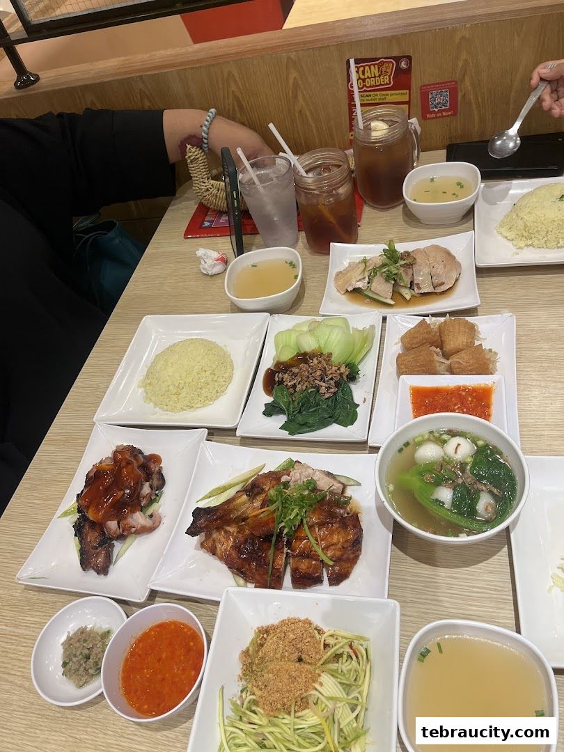 A table laden with various chicken rice dishes, side dishes, and drinks.