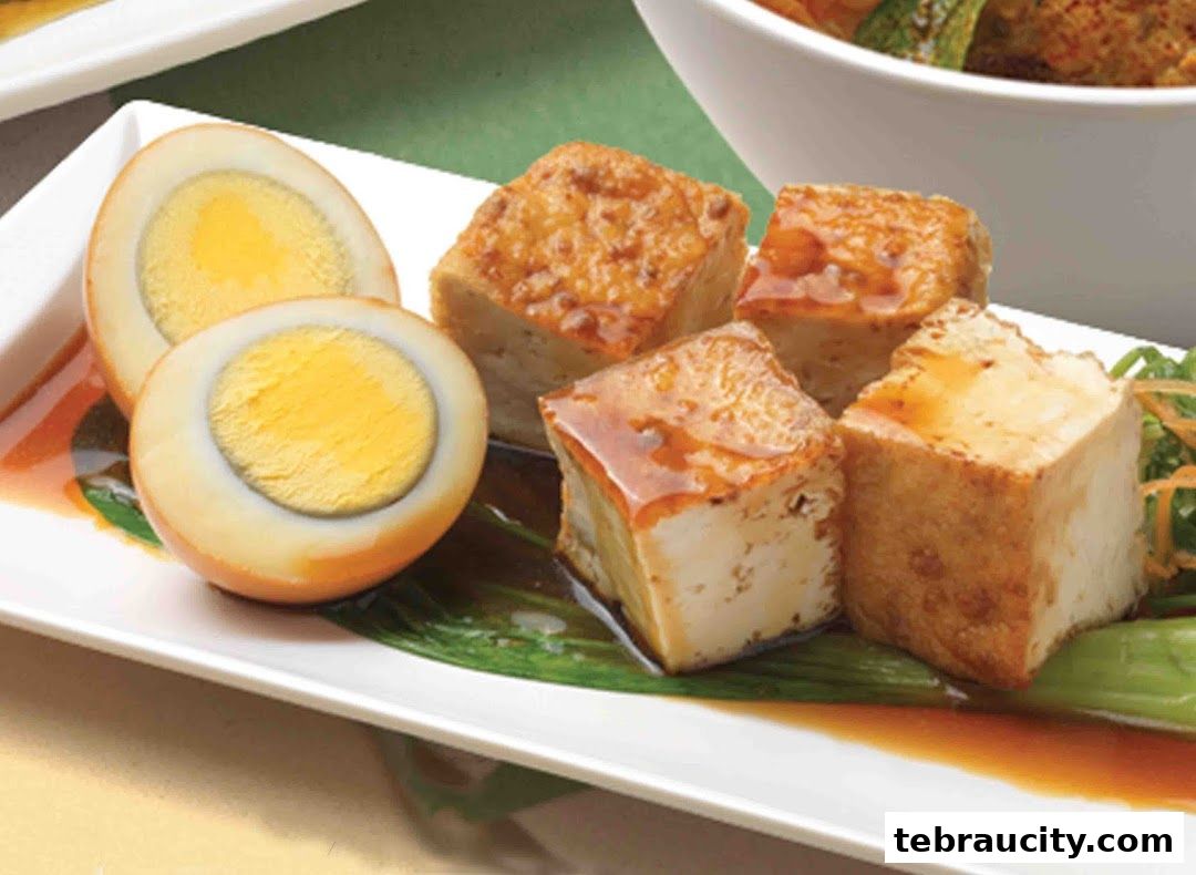 A plate of braised eggs and fried tofu cubes served with greens and sauce.