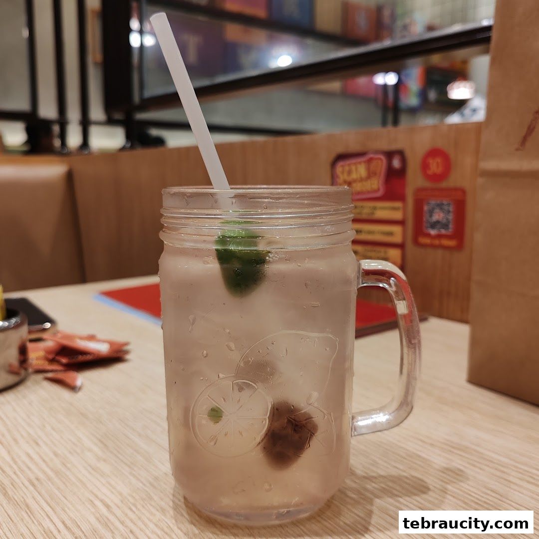 A refreshing drink with lime and plum served in a mason jar with a straw.