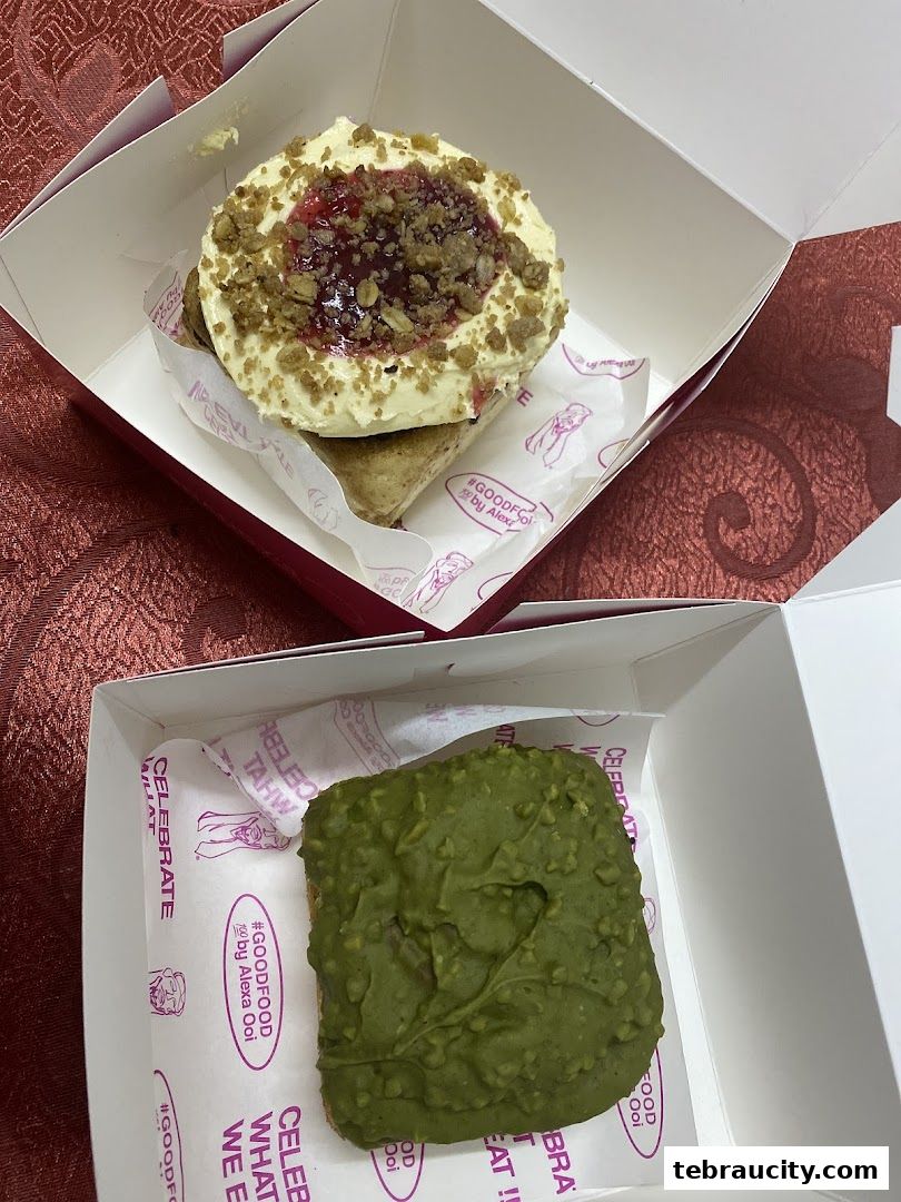 Two boxes of pastries, one with cream and berry topping, the other with green icing.