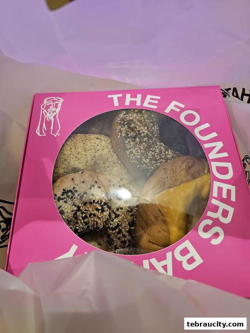 A pink box from The Founders Bakery filled with assorted bagels.