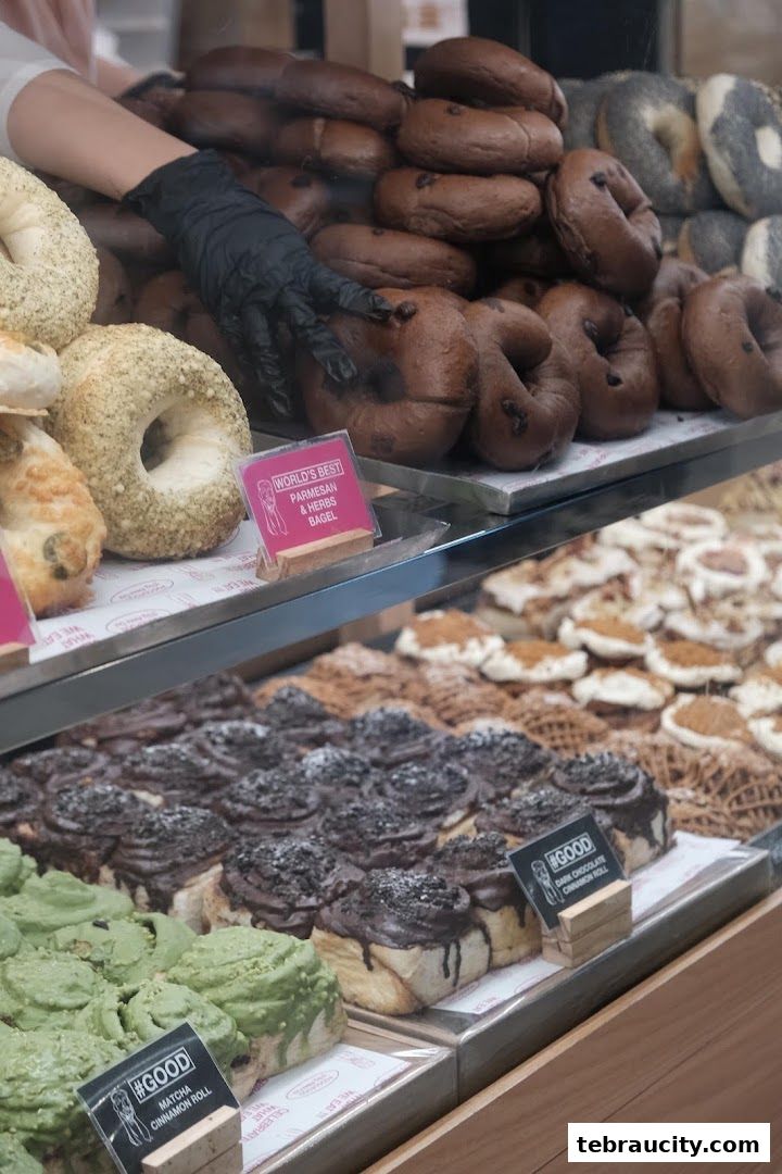 A display case filled with various baked goods, including bagels and cinnamon rolls.