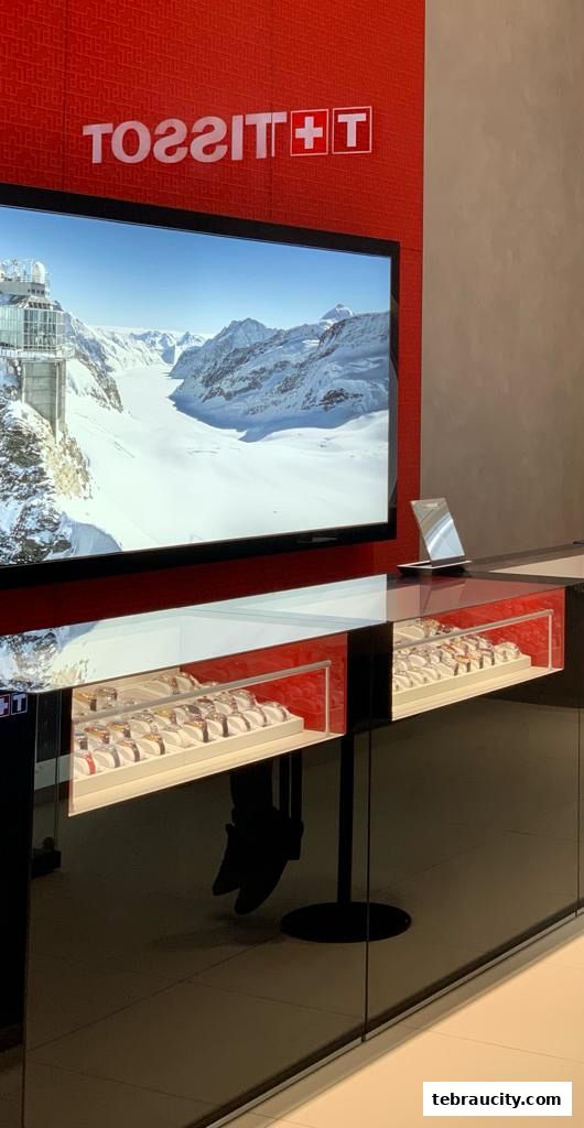 A Tissot boutique display featuring watches and a scenic mountain backdrop.