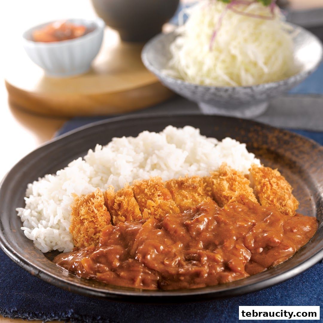 A delicious plate of tonkatsu curry with rice and a side of shredded cabbage.