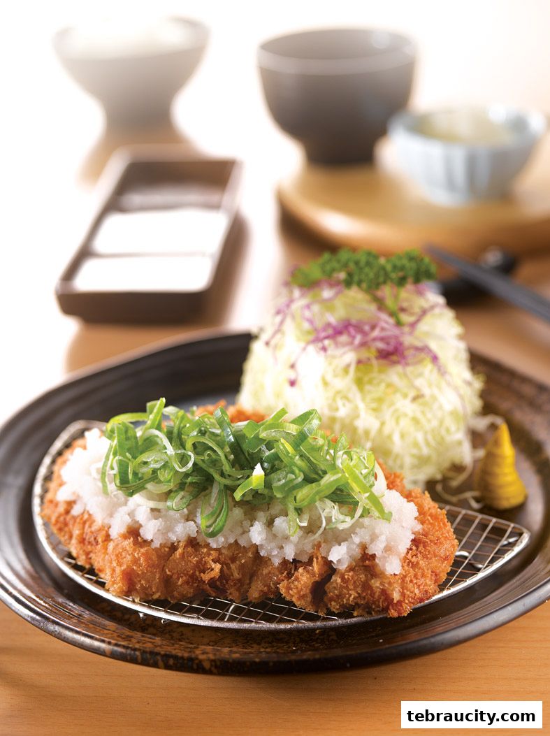 A delicious tonkatsu dish with shredded cabbage and grated radish topped with green onions.