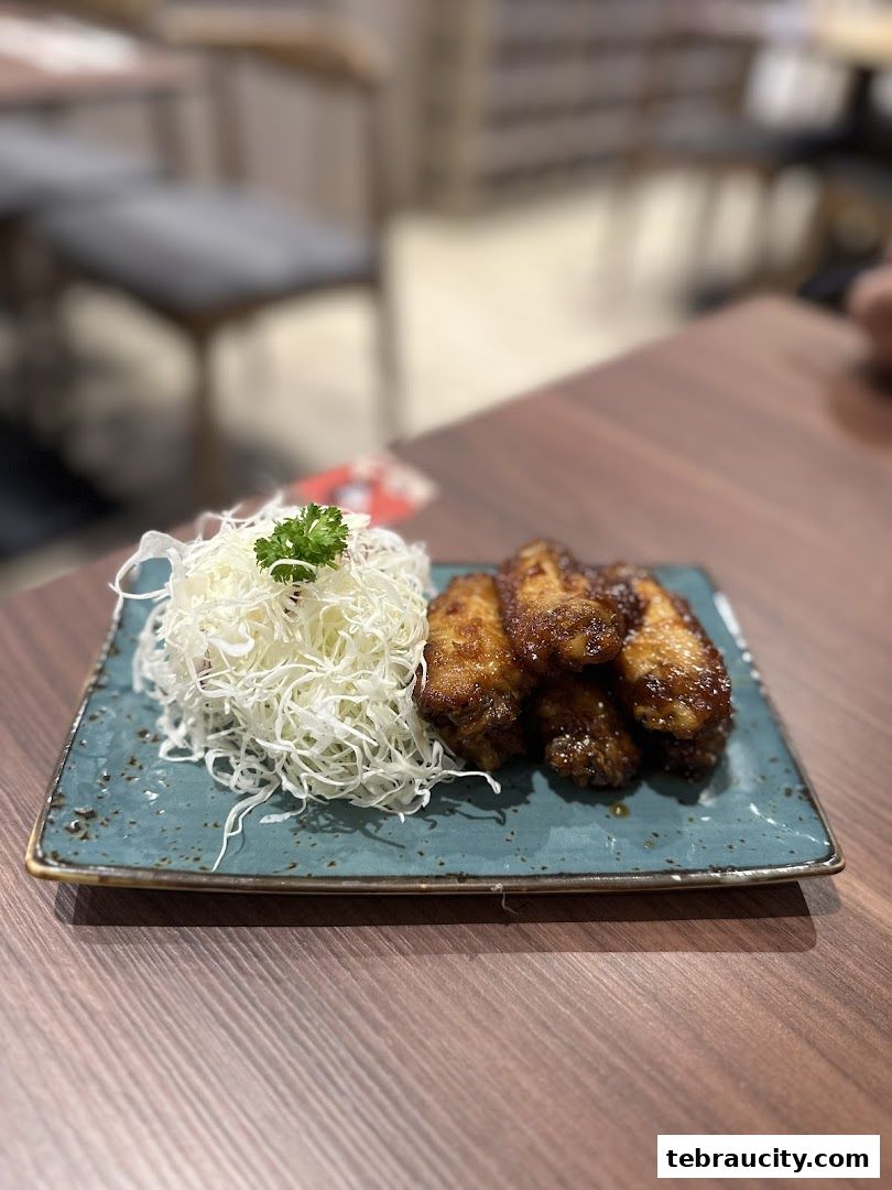 A plate of crispy fried chicken wings served with shredded cabbage and a garnish.