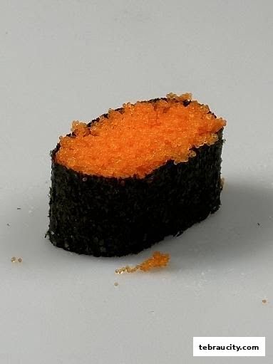 A close-up of a sushi roll with orange tobiko roe and seaweed.