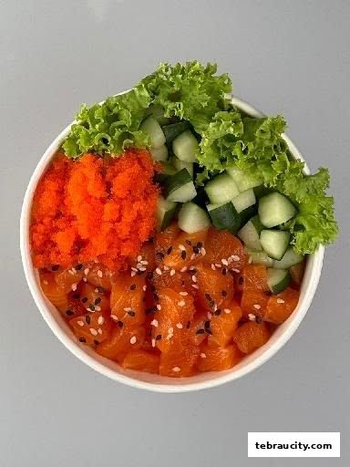 A close-up of a salmon poke bowl with tobiko, cucumber, and lettuce.