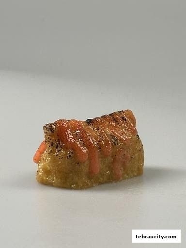 A close-up of a piece of sushi with sauce drizzled on top.
