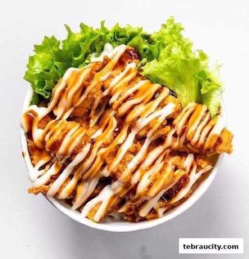 A close-up of a delicious chicken katsu donburi bowl with sauce and lettuce.