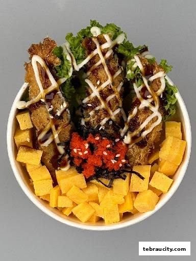 A bowl of Japanese food with fried fish, tamagoyaki, lettuce, and tobiko.