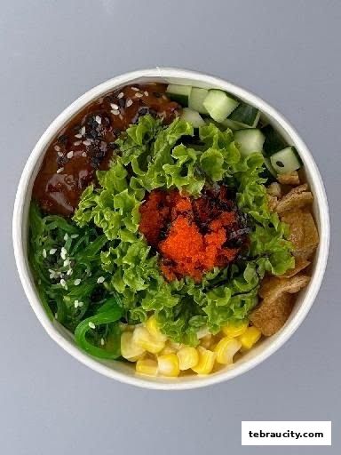 A close-up of a poke bowl with various fresh ingredients and toppings.