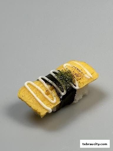 A close-up shot of a Tamagoyaki sushi roll with mayonnaise and seaweed.