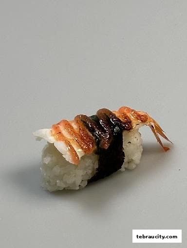 A close-up shot of a single piece of sushi with rice, seaweed, and toppings.