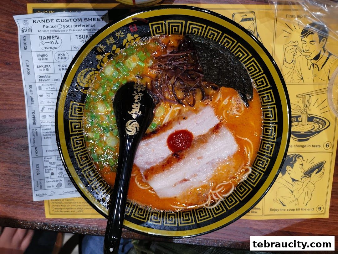 A bowl of ramen with pork, green onions, and seaweed, next to a custom order sheet.