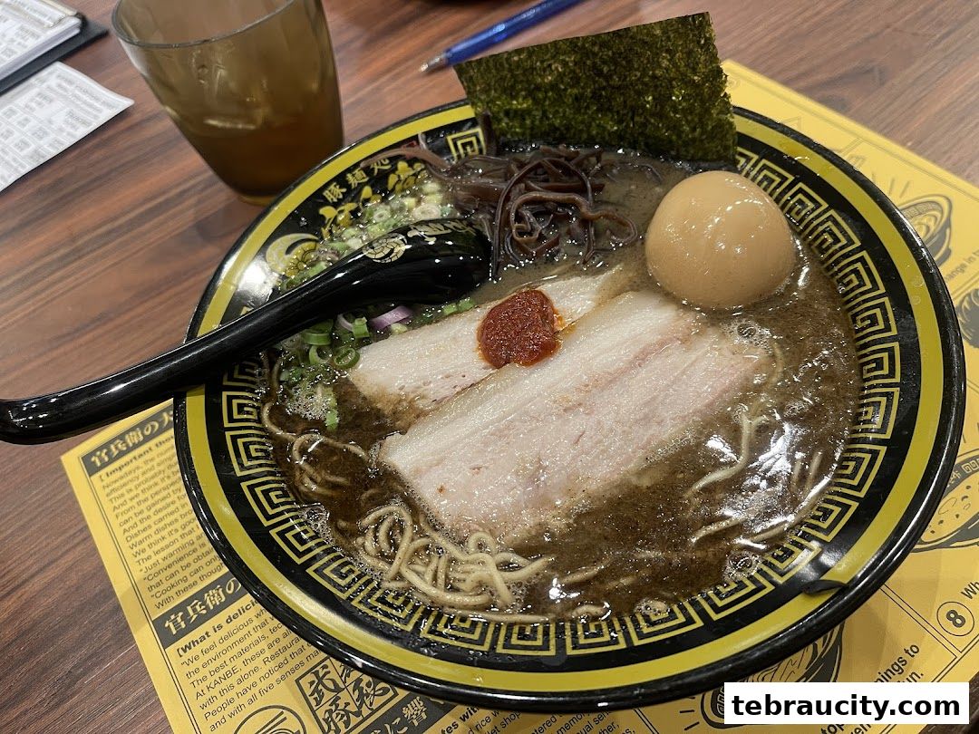 A close-up of a steaming bowl of ramen with pork, egg, and seaweed.