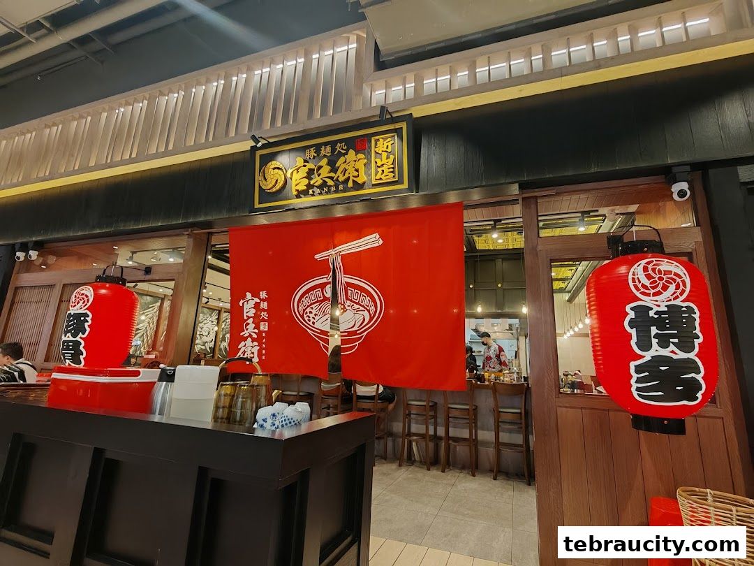 The exterior of a ramen shop with red lanterns and a large red banner displaying a ramen bowl.