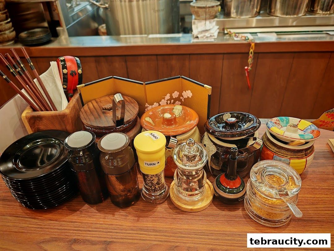 Table setting with chopsticks, plates, and various condiment containers at a ramen restaurant.