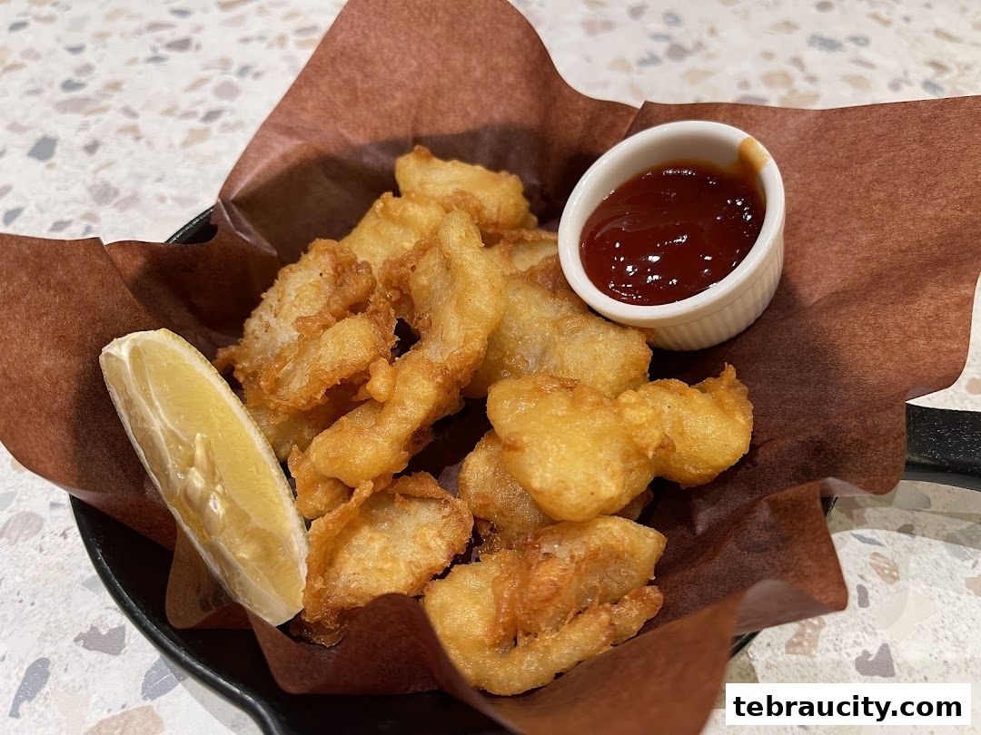 A close-up shot of crispy fried fish pieces served with ketchup and a lemon wedge.